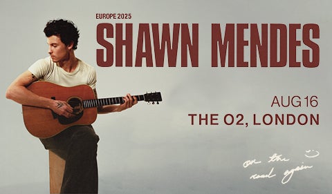 A promotional poster for Shawn Mendes’ Europe 2025 tour. The poster features a photo of Shawn Mendes seated, playing an acoustic guitar, looking down and to the side. The text reads “SHAWN MENDES, AUG 16, THE O2, LONDON, Europe 2025.” There’s a handwritten note near the bottom of the image that says “on the road again” with a smiley face doodle. Shawn is wearing a simple t-shirt and has visible tattoos on his arms.