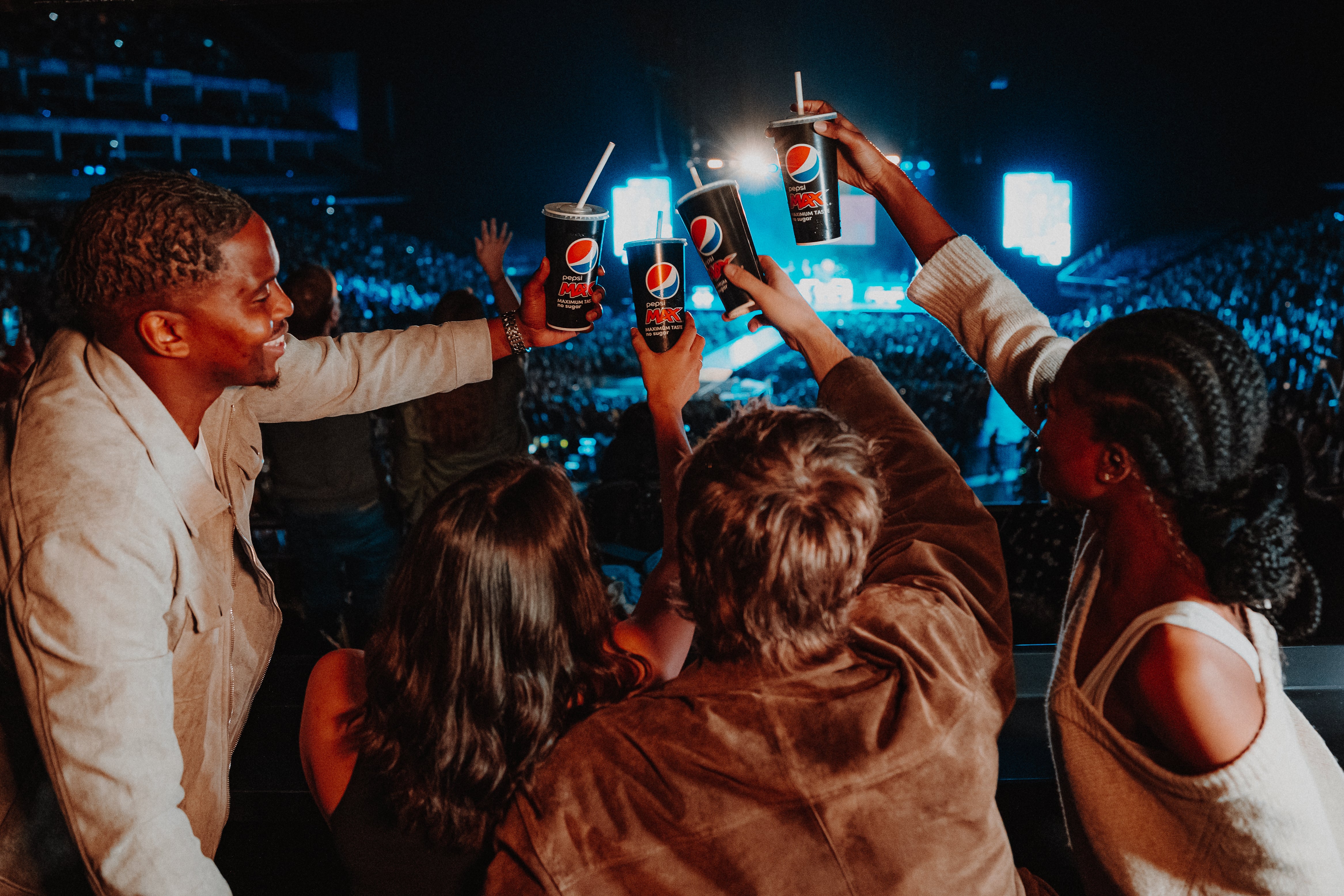 Group of people holding up Pepsi Max paper cups watching a show within The O2 arena 