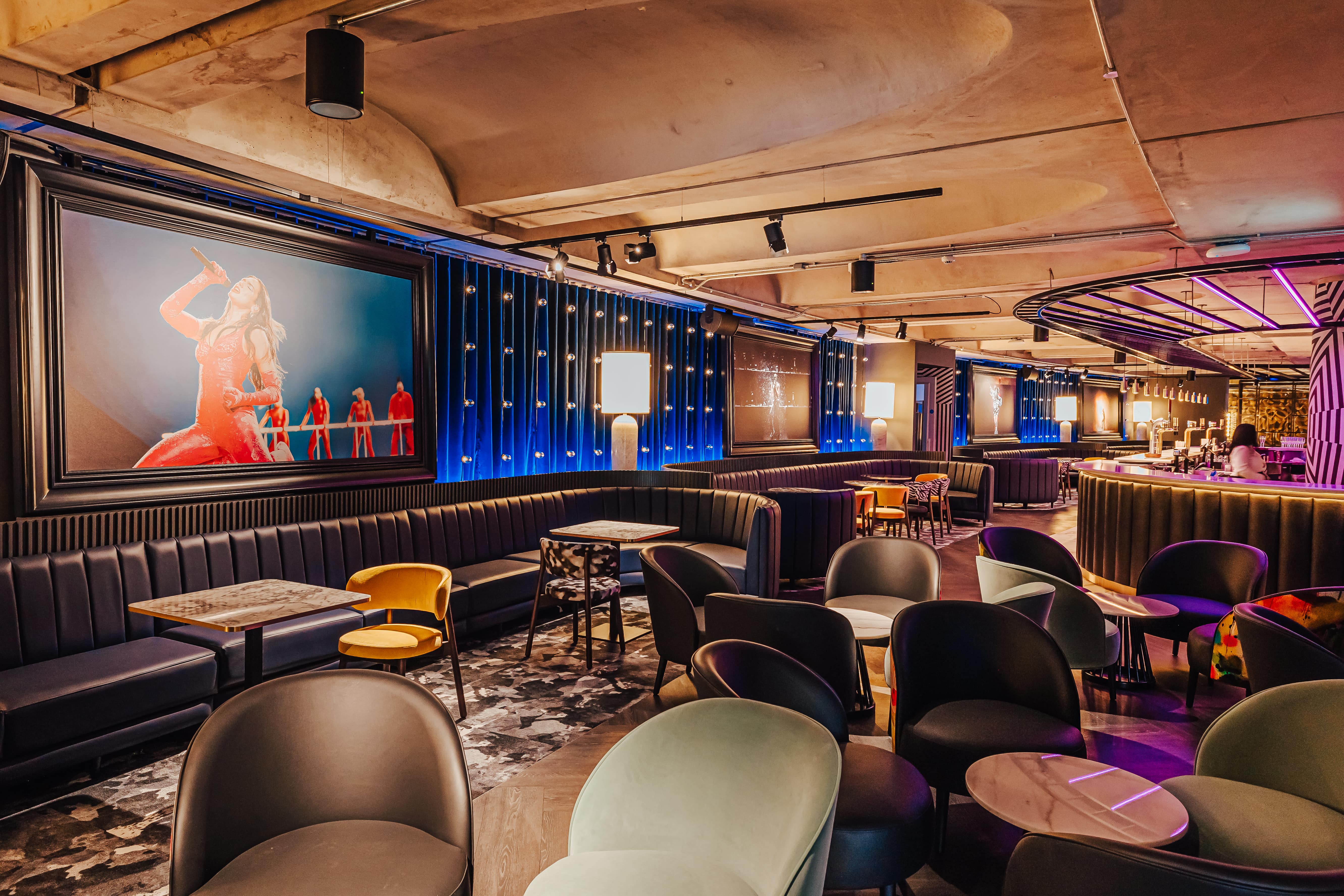 A Premium Lounge with chairs and tables, dark moody lighting with a pictures of iconic musicians on the walls 